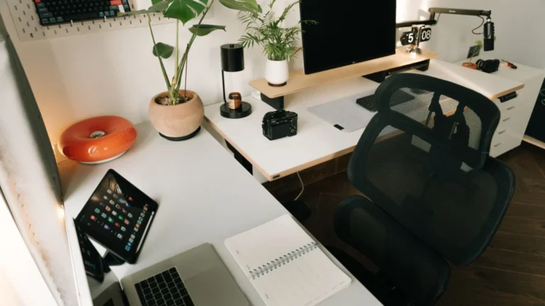 Mesa de home office organizada com monitor, tablet, acessórios e plantas