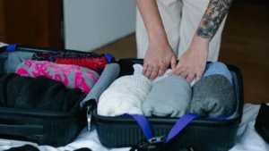 Pessoa arrumando roupas dobradas dentro de uma mala de viagem