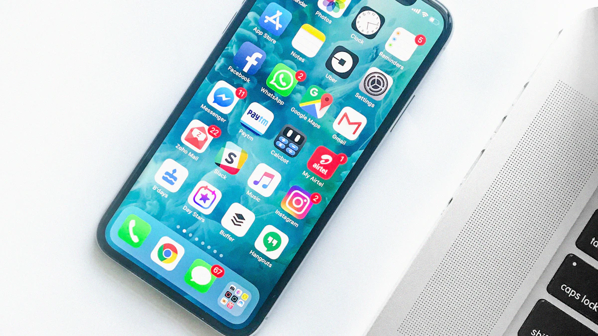 Smartphone com aplicativos na tela ao lado do teclado de um notebook