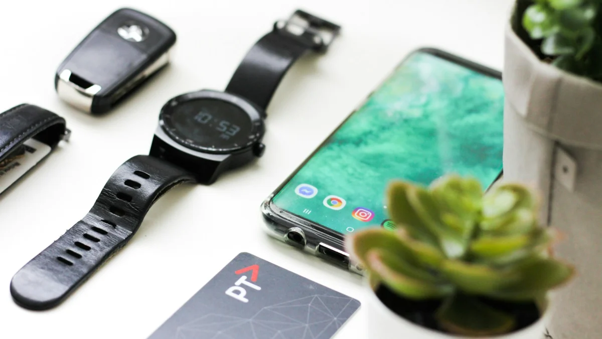 Smartphone ao lado de um smartwatch e outros acessórios sobre a mesa
