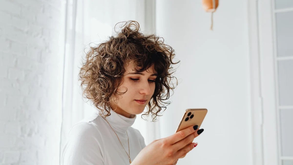 Mulher olhando o celular dentro de casa