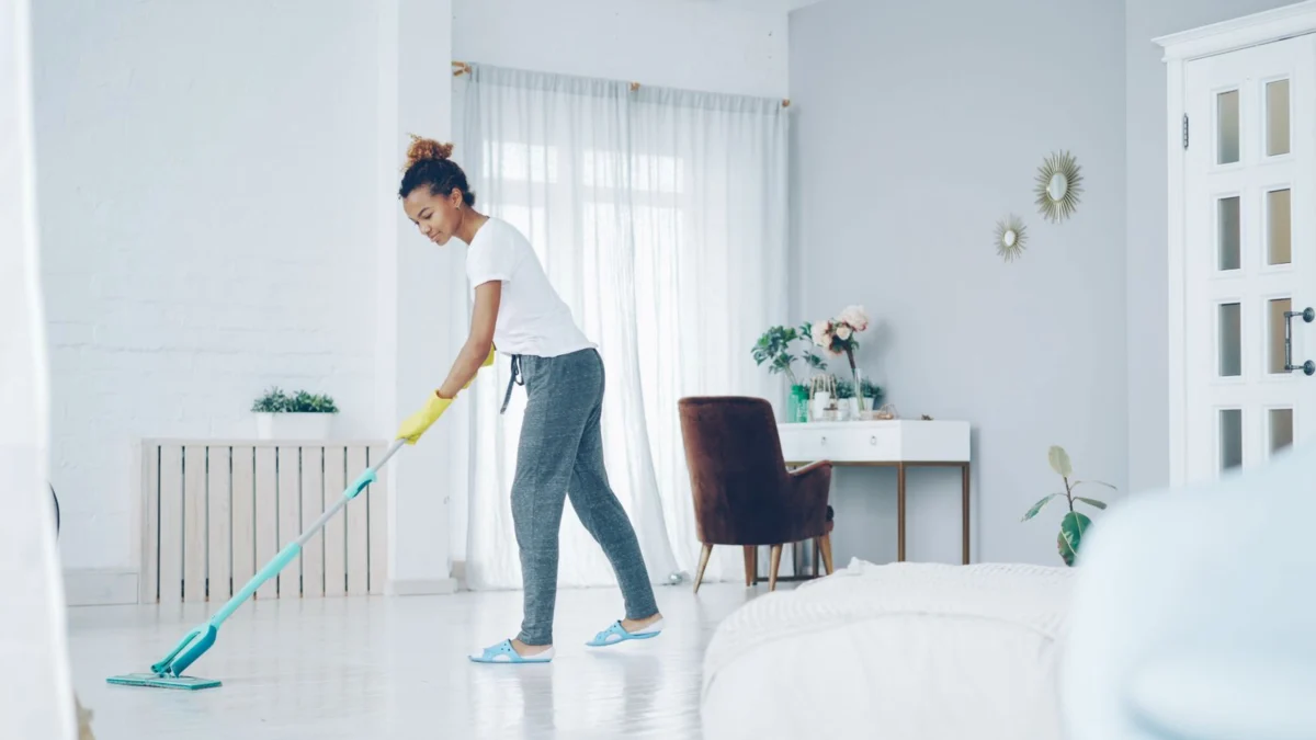 Mulher limpando o chão da sala com um mop