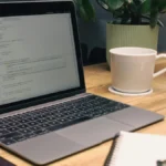 Notebook, caderno, celular e caneca sobre a mesa