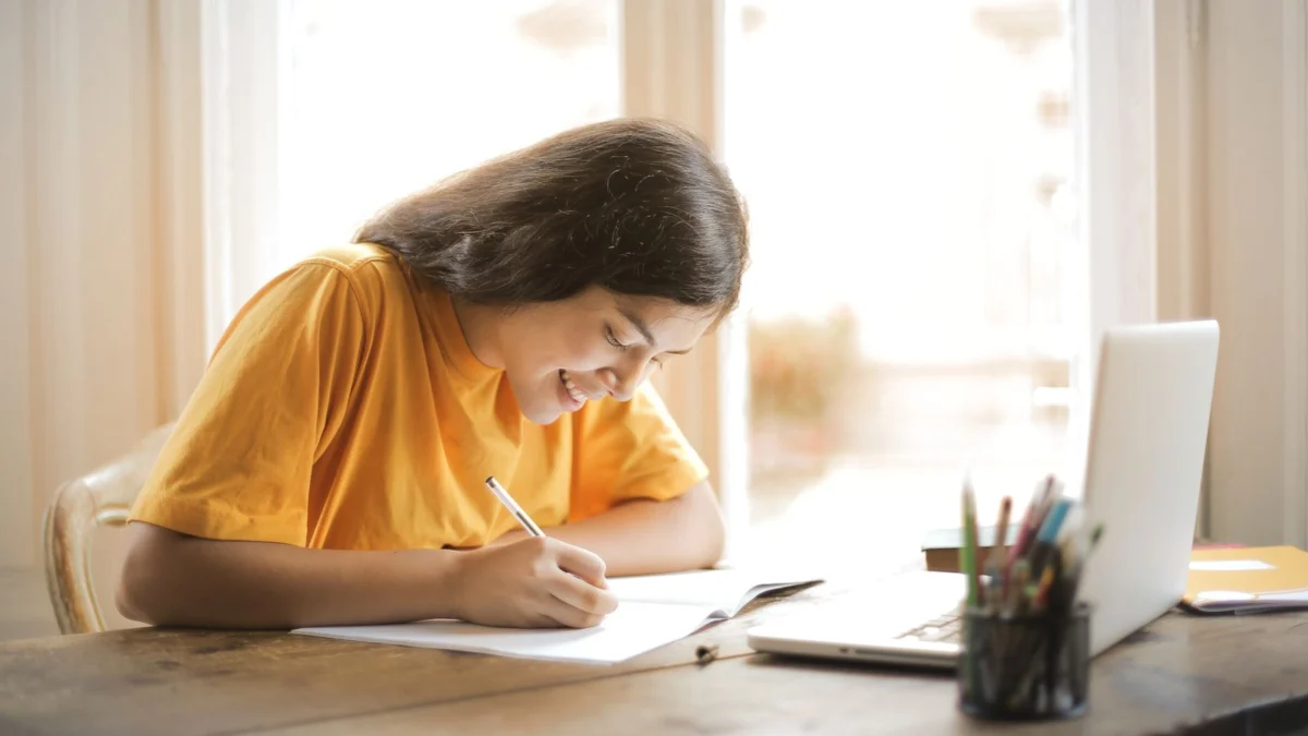 Jovem estudando em casa com notebook e caderno