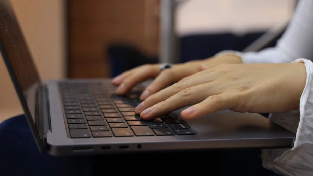Mãos digitando no teclado de um notebook