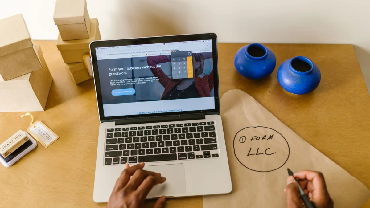 Mesa de trabalho com notebook, embalagens e anotações de um pequeno negócio